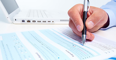 Man filling out a form; laptop in background