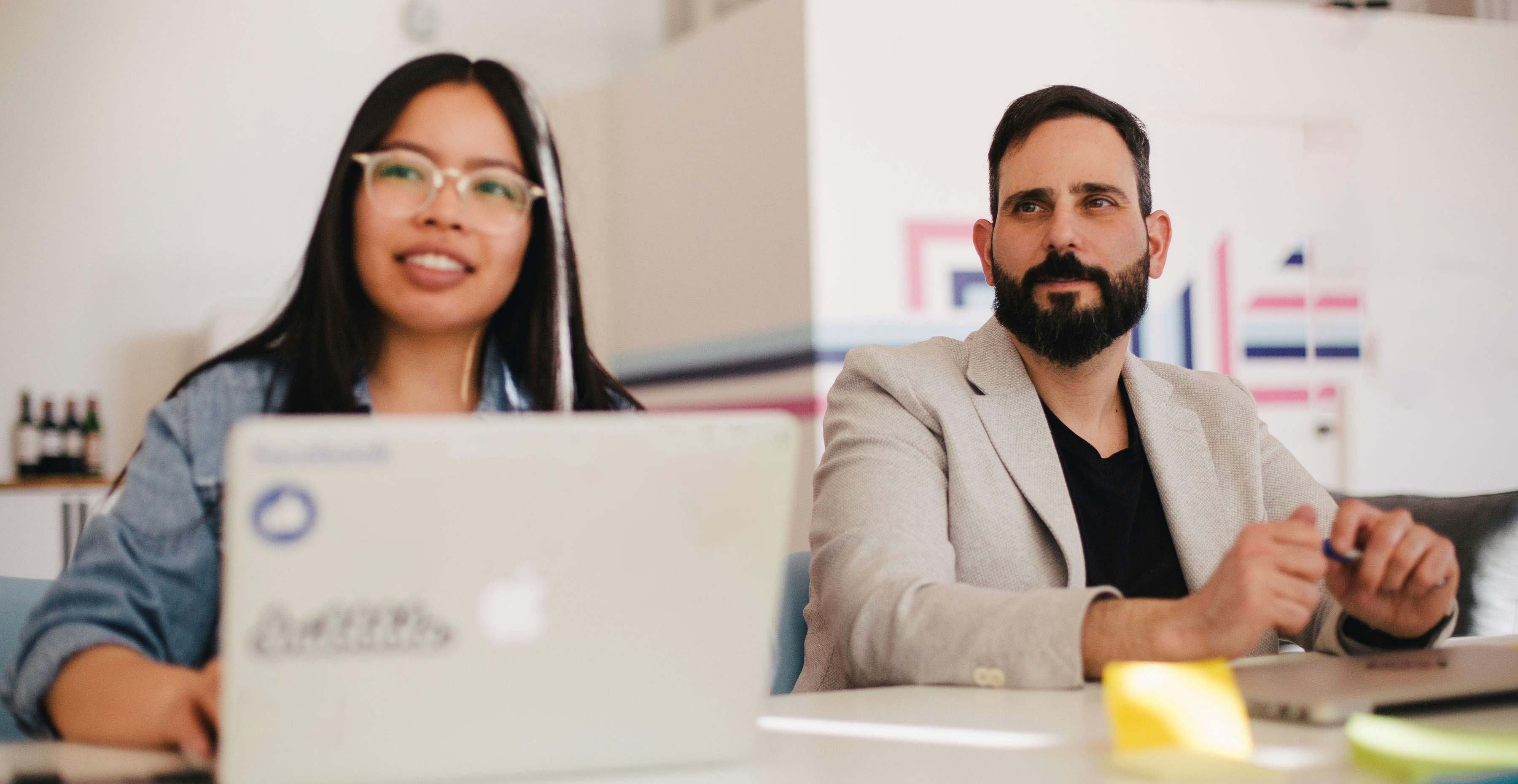 A woman with a laptop sitting next to a man at a table