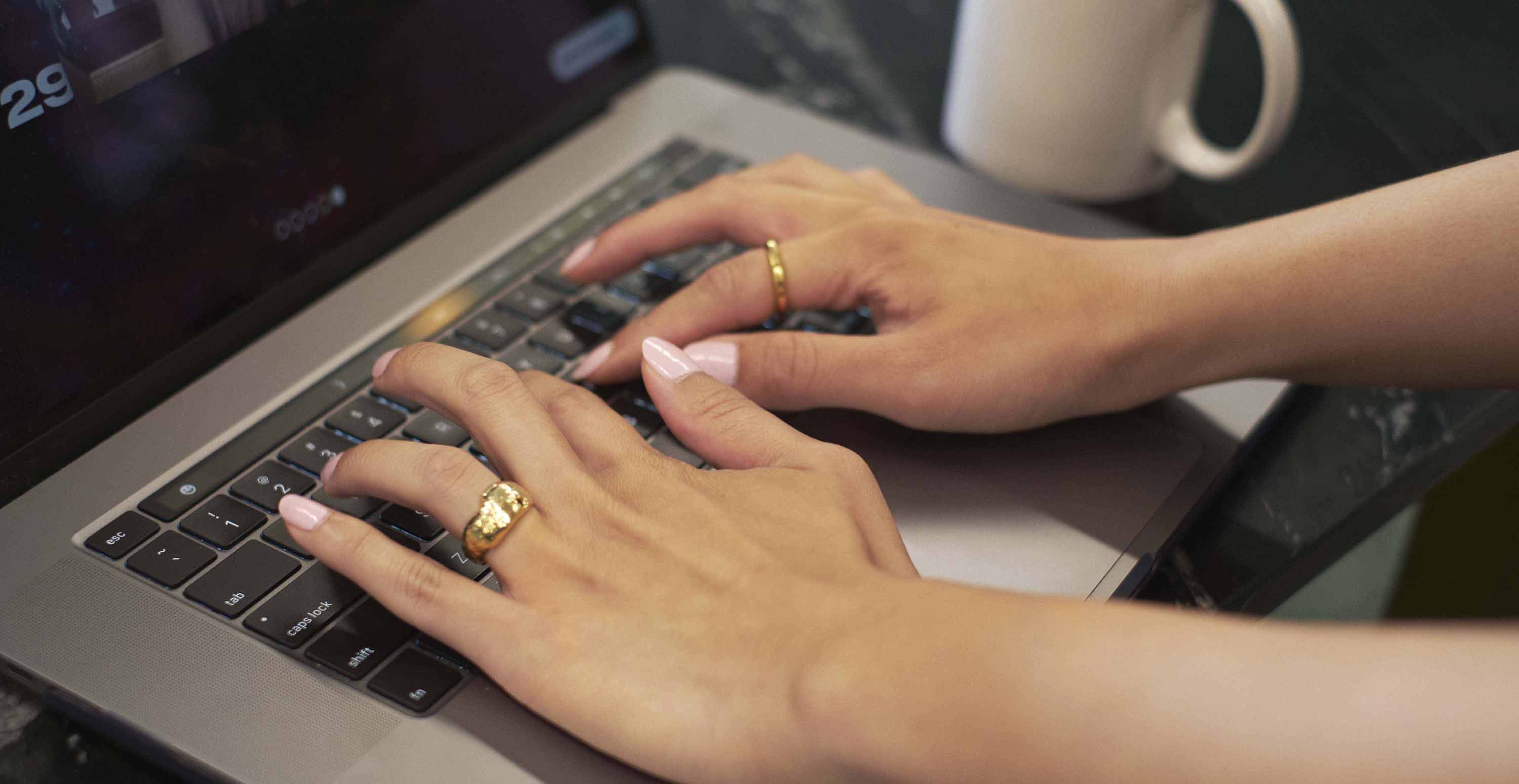 Hands typing on a laptop keyboard